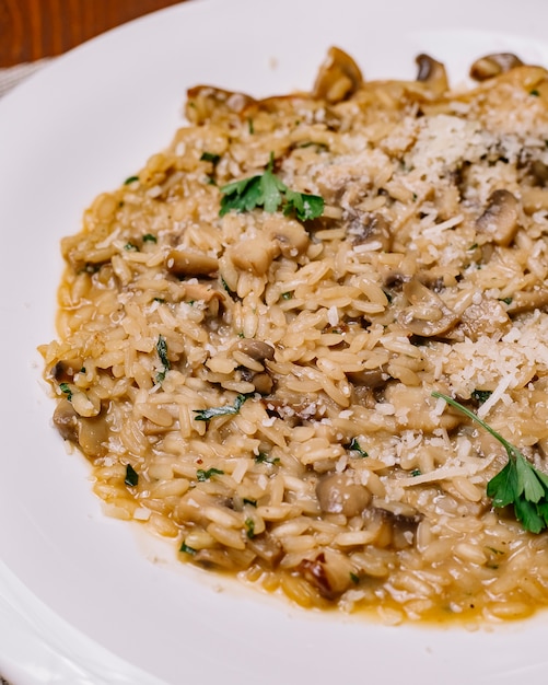 Risotto met champignons gegarneerd met geraspte parmezaanse kaas en peterselie verticaal