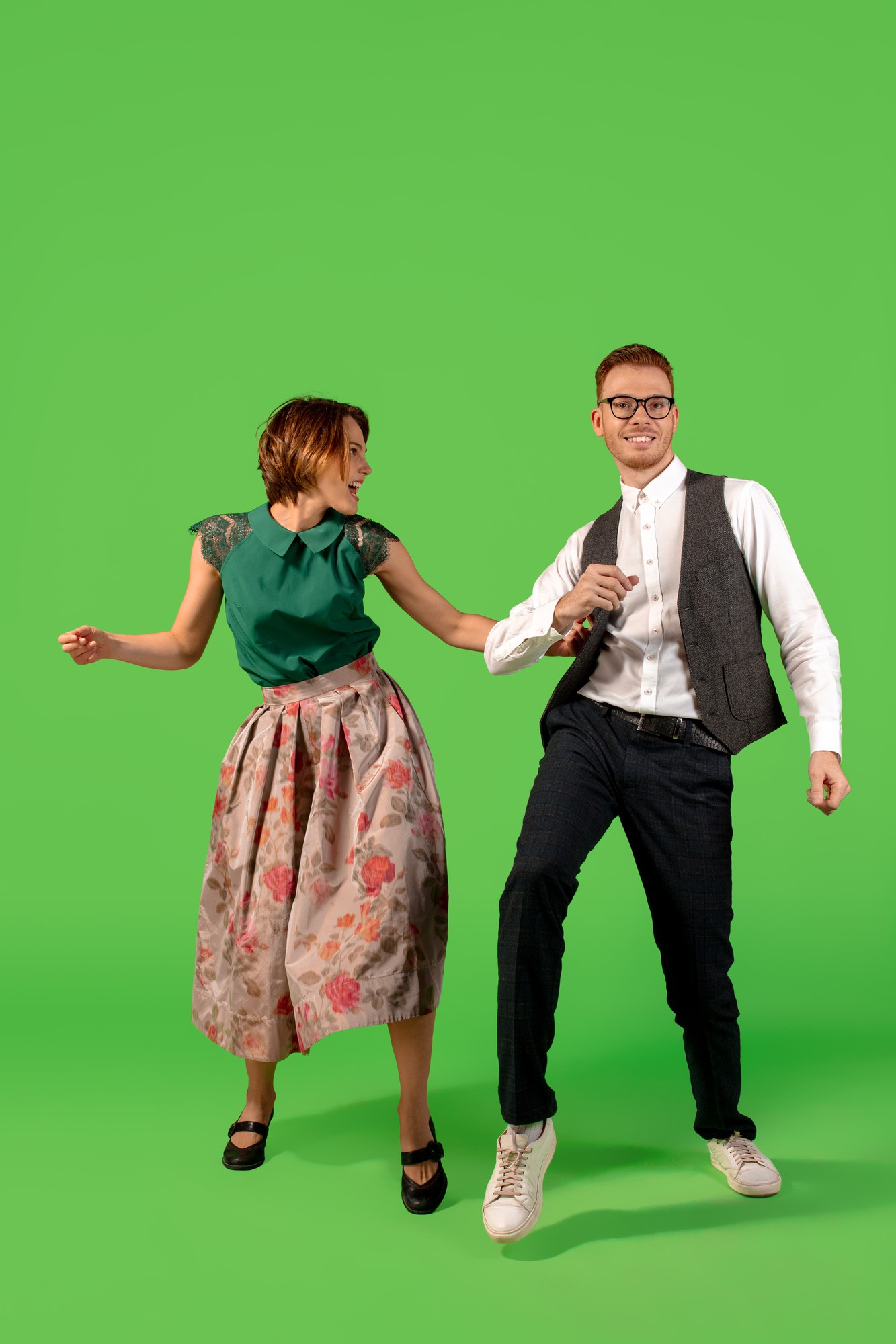 Rock n roll. Old-school ouderwetse jonge vrouw dansen geïsoleerd op groene studio achtergrond. Jonge stijlvolle man en vrouw.