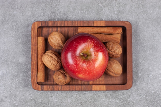 Rode appels, okkernoten en pijpjes kaneel op houten plaat