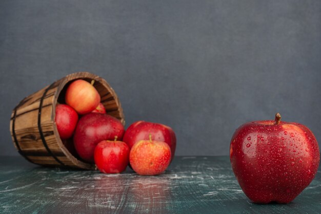 Rode appels vallen uit emmer op marmeren tafel.