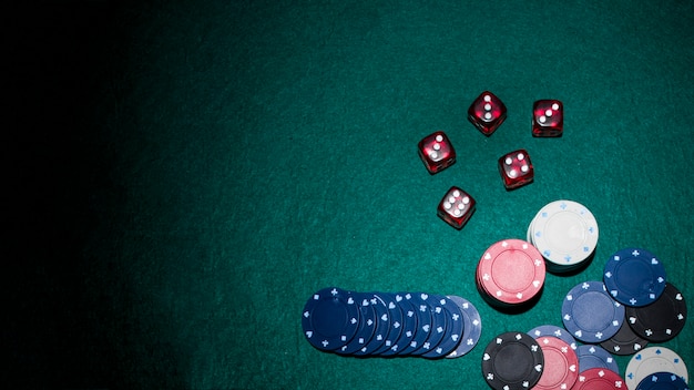 Gratis foto rode dobbelstenen en casinofiches op groene pokertafel