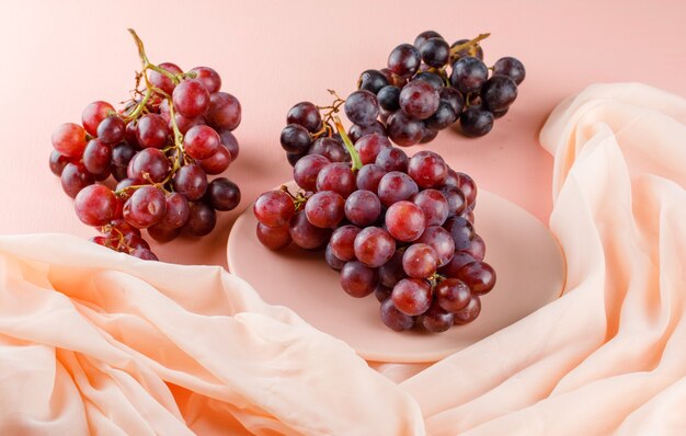 Rode druiven in een plaat op roze en textiel. hoge kijkhoek.