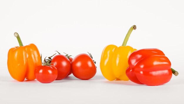 Rode en gele paprika met tomaten op wit