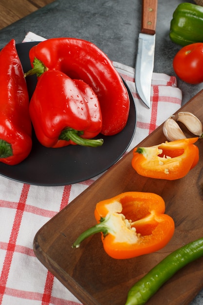 Gratis foto rode en gele paprika op een geruite handdoek. bovenaanzicht