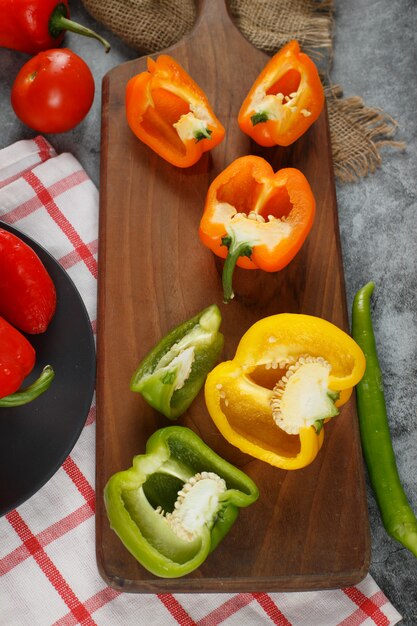 Rode, gele en groene paprika op een houten bord. Bovenaanzicht