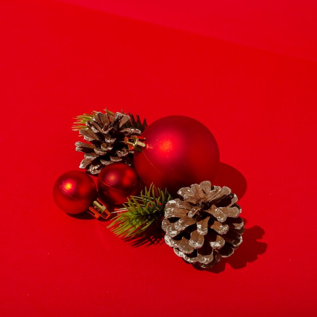 Rode kerstballen en dennenappels op rode tafel