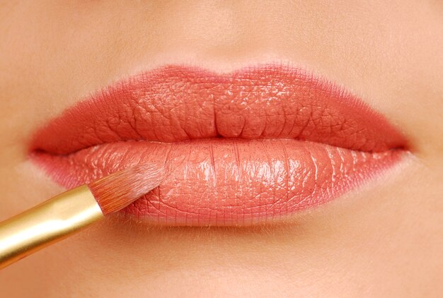 Rode lippenstift cosmetische borstel. Make-up hulpmiddel. Vrouw lippen close-up.