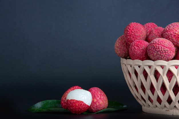 Rode litchifruit die in een mand wordt geplaatst.
