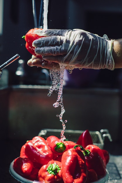 Rode paprika's wassen onder de kraan. Hoge kwaliteit foto