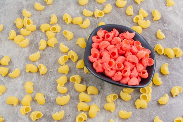 Rode pasta's in een tomatensaus in keramische kopjes op de grijze ruimte.