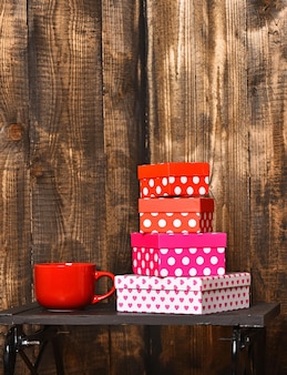 Rode thee- of koffiekop of keramische mok voor drank en mooie zoete cadeaudozen zwarte lade op houten achtergrond, kopieer ruimte