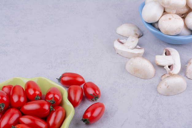 Rode tomaten en champignons op grijze ondergrond