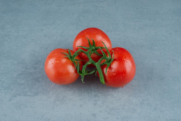 Rode tomaten met waterdruppels op blauw.