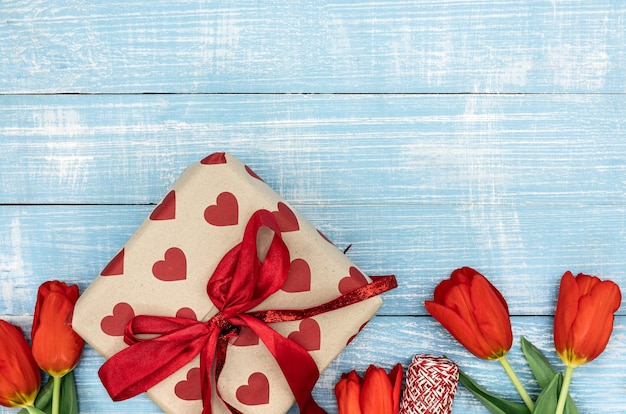 Rode tulpen en een geschenkdoos op een blauwe houten achtergrond bovenaanzicht