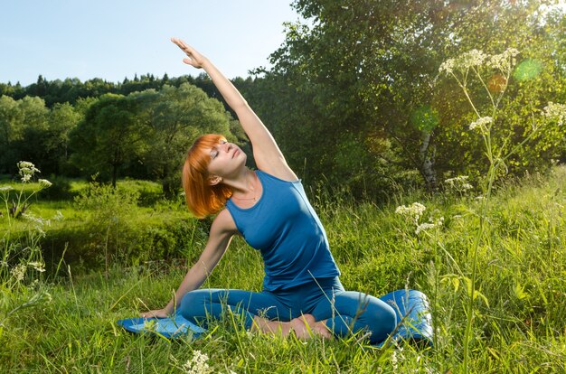 Rode vrouw oefenen fitness yoga buitenshuis