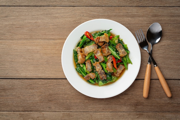 Roergebakken boerenkool, pittig krokant varkensvlees op houten tafel Thais eten concept.