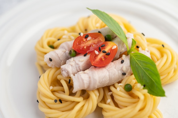 Roergebakken spaghetti en varkensvlees, mooi gerangschikt in een wit bord.