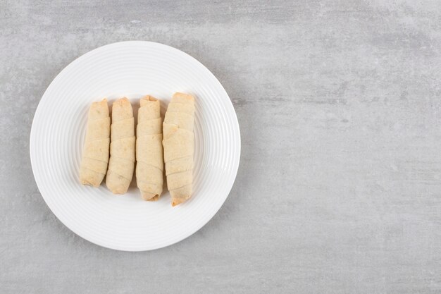 Rol koekjes op een bord, op de marmeren tafel.