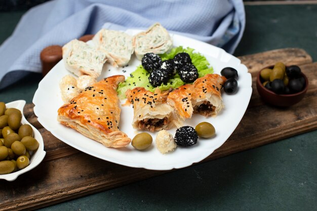 Rol salade met gebak en olijven in een witte plaat