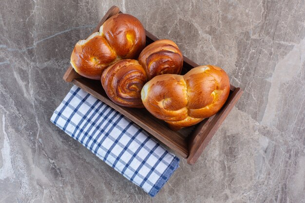 Rol tafelkleed en een mandje met zoete broodjes op marmer.