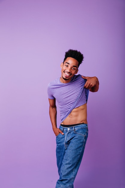 Romantisch Afrikaans model dat zijn t-shirt opstijgt. Indoor foto van lachende schattige zwarte man.