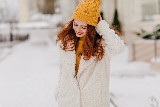 Romantisch gembermeisje die tijdens openluchtfotoshoot neerkijken. Sierlijke blanke dame stad wandelen in de winter.