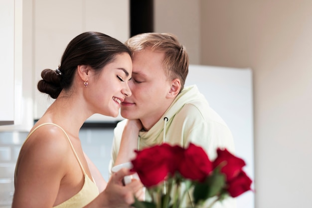 Gratis foto romantisch paar dat thuis valentijnsdag viert met een boeket van mooie rode rozen