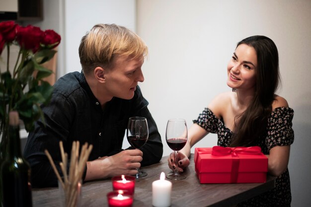 Romantisch paar dat Valentijnsdag thuis viert met wijn en cadeau