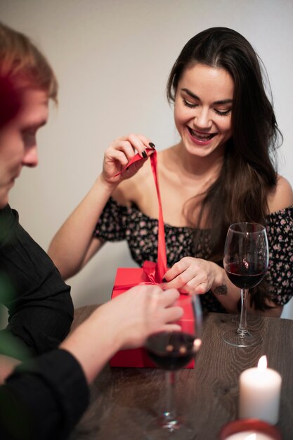 Romantisch paar dat Valentijnsdag thuis viert met wijn en cadeau