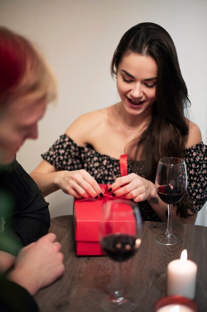 Romantisch paar dat Valentijnsdag thuis viert met wijn en cadeau