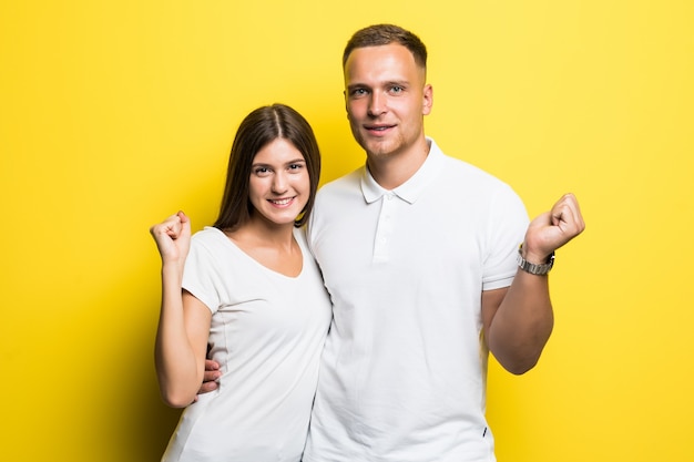 Romantisch paar geïsoleerd op gele achtergrond knuffelen samen gekleed in witte t-shirts