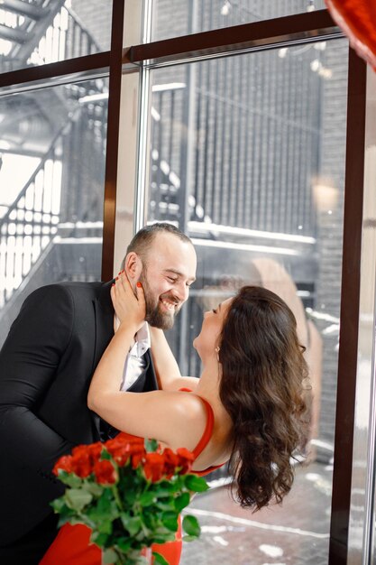 Romantisch paar staande in restaurant op een date in de buurt van groot raam en knuffelen