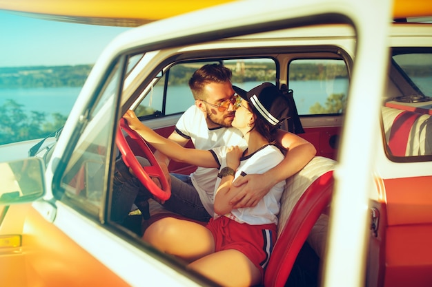 Romantisch paar zittend in de auto tijdens een road trip lachen op zomerdag