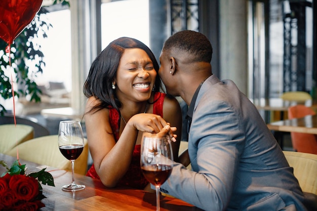 Romantisch zwart stel dat in een restaurant zit en elegante kleding draagt