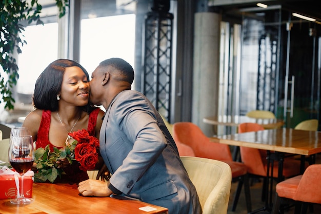 Romantisch zwart stel dat in een restaurant zit en elegante kleding draagt