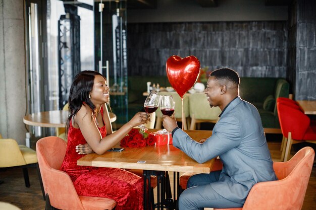 Romantisch zwart stel dat in een restaurant zit en elegante kleding draagt