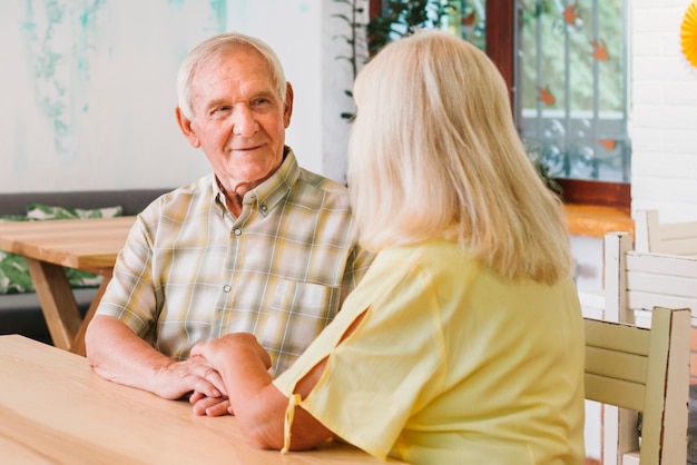 Romantische hogere paarzitting in koffie en hand in hand