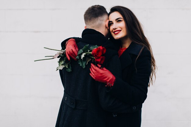 Romantische vrouw met bloemen die de mens omhelzen