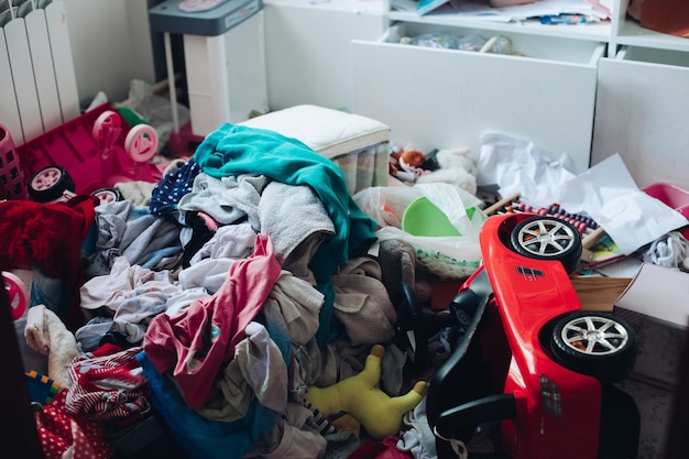 Rommelig kamer- en wanordeconcept in de woonkamer of slaapkamer. Verspreide kleding en spullen op de grond.