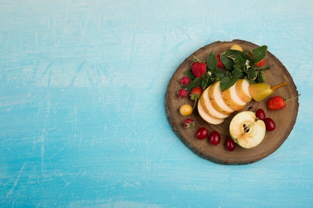 Ronde fruitschaal met peren, appel en bessen aan de rechterkant