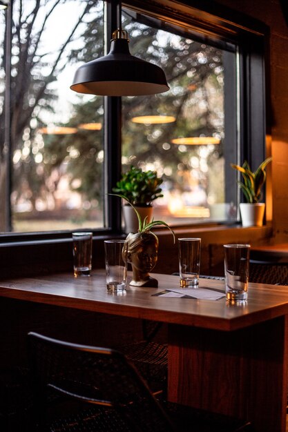 Ronde heldere drinkglazen op bruine houten tafel en ronde zwart-witte hanglamp