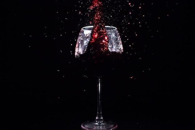 Rood sap spat in een kristalglas in de zwarte ruimte