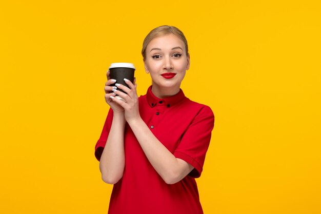 Rood shirt dag mooi meisje met koffiekopje in een rood shirt op een gele achtergrond