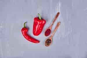 Gratis foto roodgloeiende spaanse pepers met paprika en peper in houten lepels.