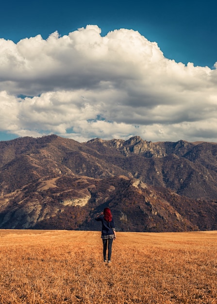 Roodharig meisje in de gouden velden met de rotsachtige bergen op de achtergrond