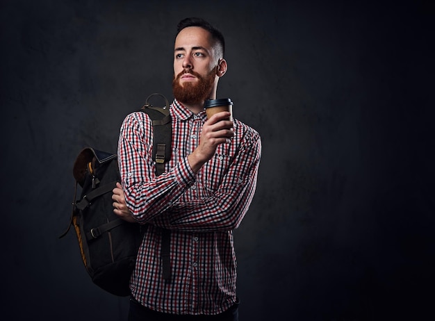 Roodharige bebaarde hipster man in een rood fleece shirt houdt smartphone over grijze achtergrond.