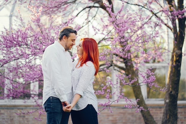 roodharige vrouw in een witte blouse staat in een zonnige zomer park met haar vriendje