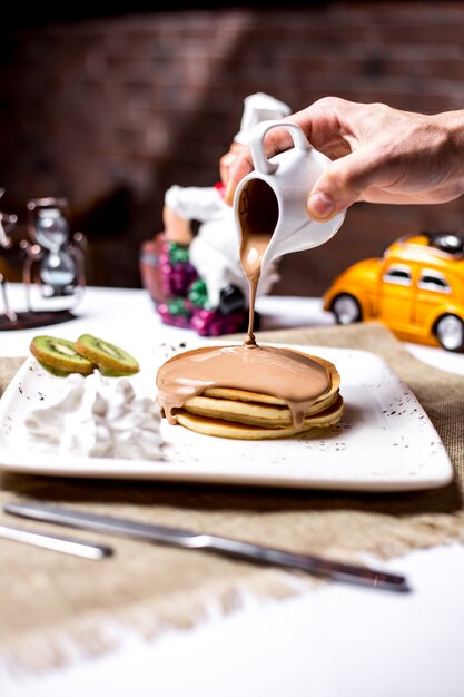 Room van de mensen de gietende chocolade op pannekoek zijaanzicht