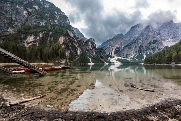 Rotsachtige bergen bedekt met sneeuw weerspiegeld in Braies Lake in Italië onder de onweerswolken