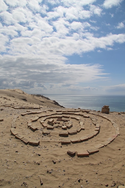 Rotsen vormen een cirkel op het zandstrand onder de bewolkte hemel